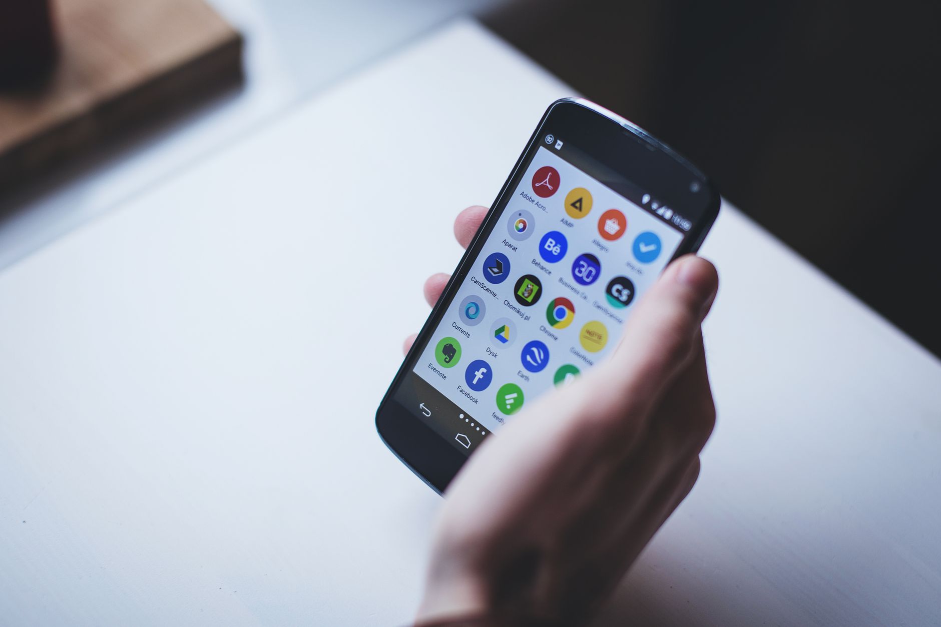 Hand holding a smartphone with app icons